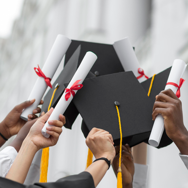 Image of students' hands hold diplomas aloft