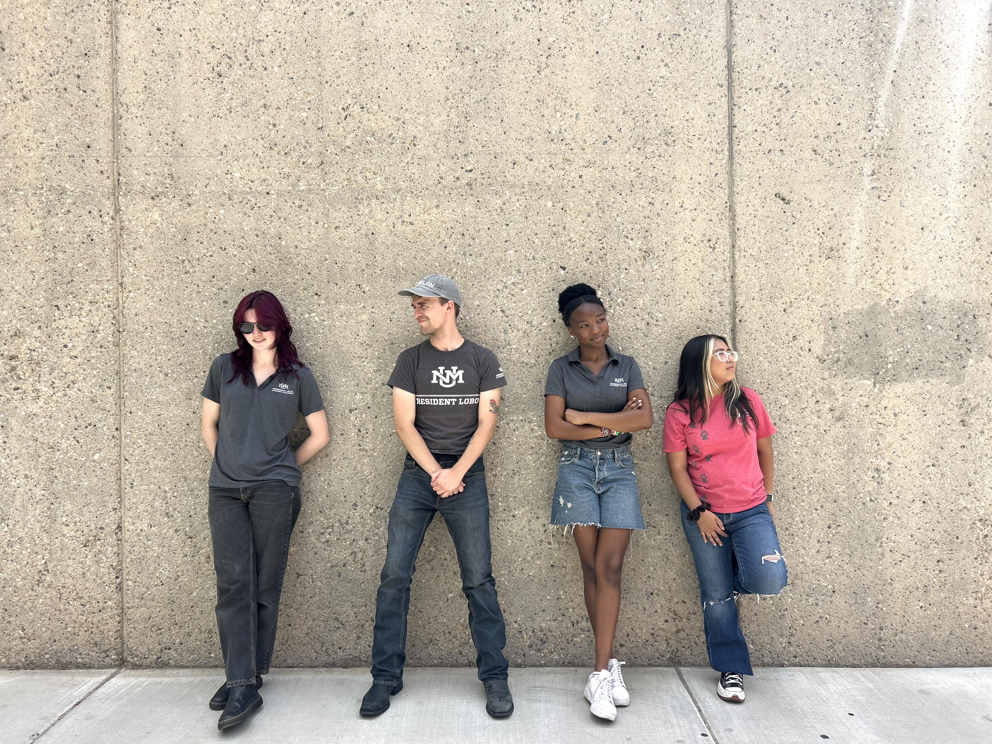 Four UNM Housing Ambassadors standing next to a wall