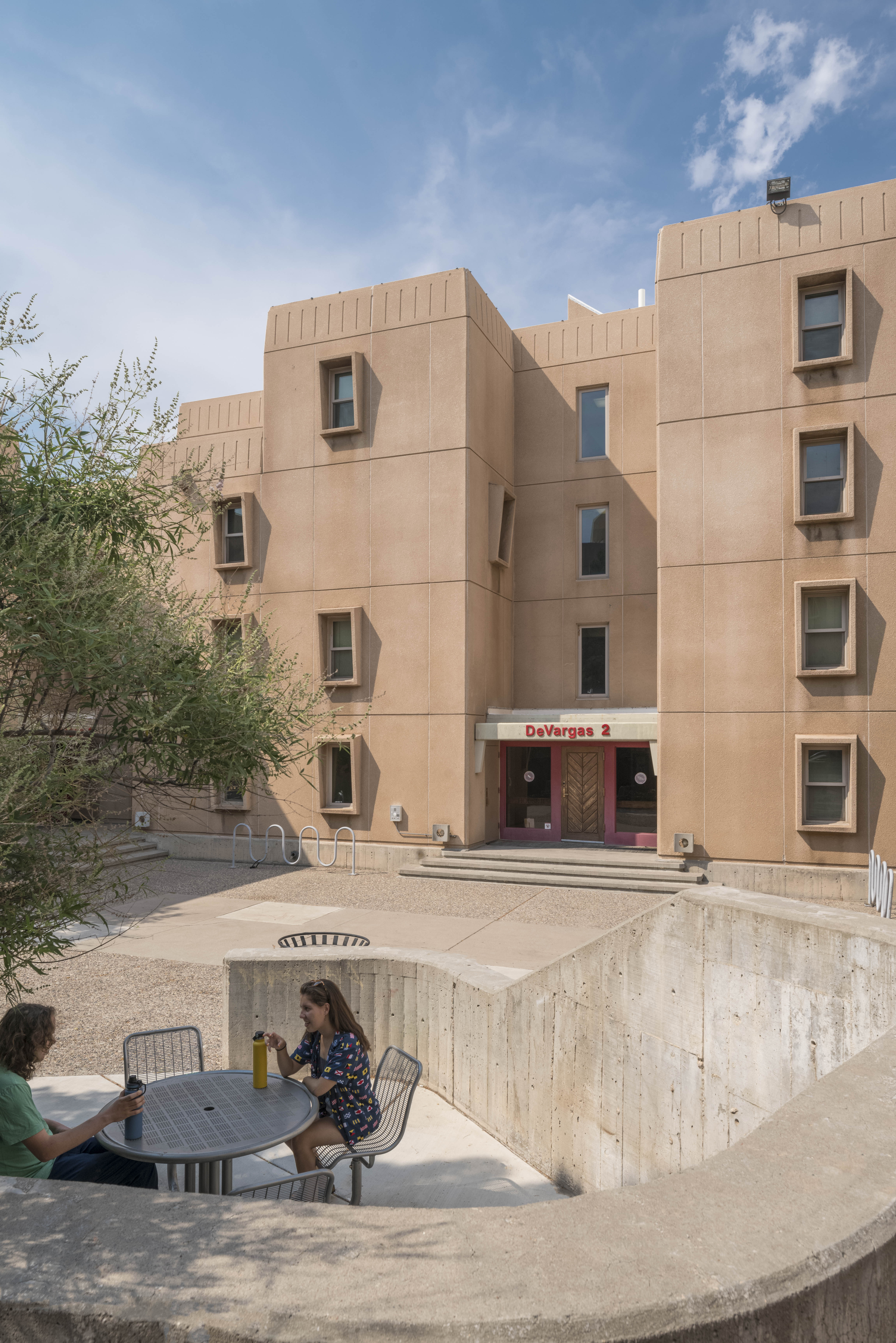 Two students sitting on a patio in front of DeVargas Hall